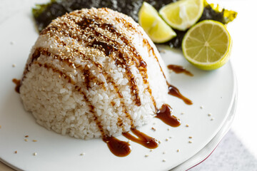 Close-up, rice topped with sauce and sprinkled with sesame seeds.