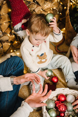 Fototapeta na wymiar Kids have fun together in winter holidays. Child playing with decorations toys, preparing to decorate Christmas tree. Large big family with children. Happy New Year. Decorated interior home. Top view