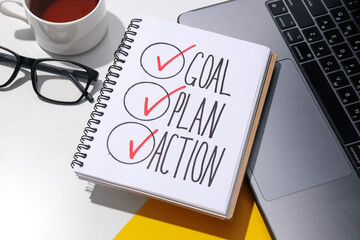 Goal plan in notebook with laptop and tea