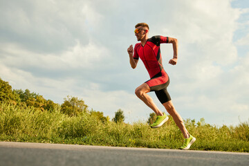 Professional athlete, man in sportswear training outdoors on warm sunny day. Running along the...