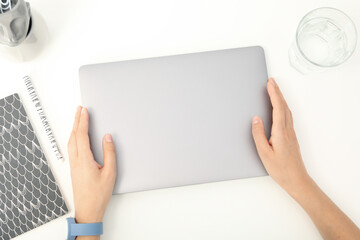 Notepad, glass and laptop in hands on white background, top view