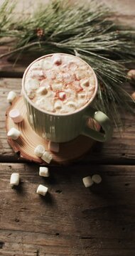 Vertical video of mug of chocolate, marshmallows and copy space on wooden background