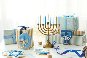 Hanukkiah, gingerbread and gift boxes on light background