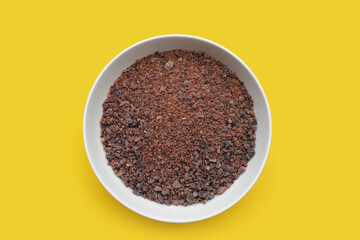 Black himalayan salt in white bowl on yellow background.