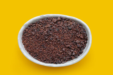 Black himalayan salt on yellow background.