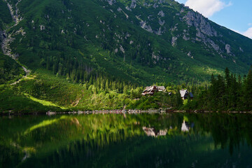 View on cabin in mountains with green forest. House for tourists in Tatra National Park near Morskie Oko or Eye Sea lake. Touristic place in Poland - obrazy, fototapety, plakaty