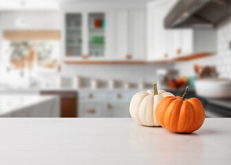 Autumn pumpkins on white wooden kitchen table pr counter with kitchen background.