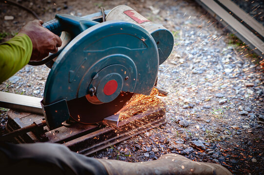 The industrial use of a metal cutting saw involves heat and sparks from skilled technicians.