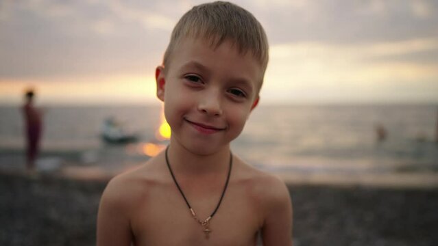 Happy little boy with smiling and laughing on tropical beach at sunset. Young child having fun in summer holiday vacation travel. Summer vacation concept. Close up face of cute child. Kid outdoor