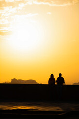 Sunset and lovers. Woman and man against the backdrop of sunset. Orange sky and sun