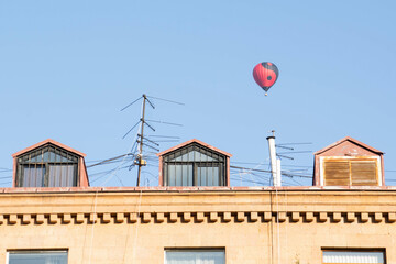 Fototapeta na wymiar Roof of a house and a hot air balloon in the sky. Residential building and hot air balloon.