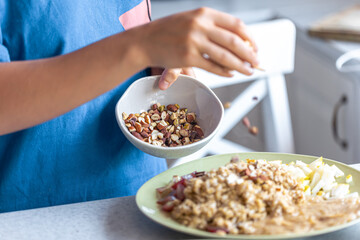A woman prepares oatmeal with fruits, close-up.