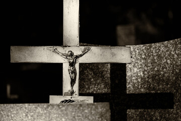 CEMETERY - An old crucifix with a figurine of Jesus on a tombstone