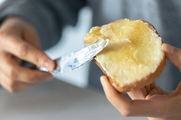 Woman spreading jam on toast, close up.