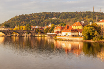 Fototapeta na wymiar Autumn views from Prague. Picturesque autumn Prague in the morning sun. The Vltava River with the Charles Bridge, the waterfront and houses of Mala Strana and the dominant Prague Castle. Czechia