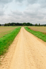 Rural landscape with gravel country road in summer