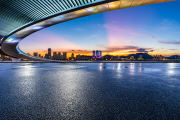 Asphalt road and city skyline at sunset
