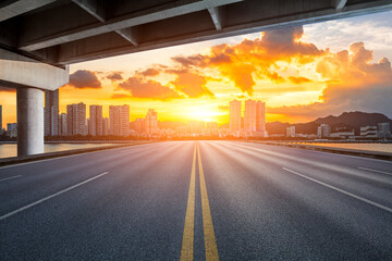 Straight asphalt road with residential area buildings scenery at sunset