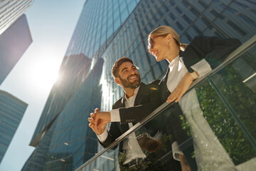 Two managers talking during break standing on terrace on background of modern office building