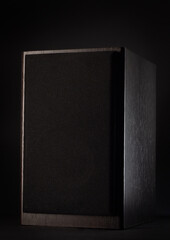 Photo of a black speaker on a black background in the dark.
