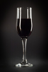 Glass of red wine on a black background. Wineglass with red wine.