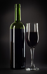 bottle and glass of red wine on a black background with copy space