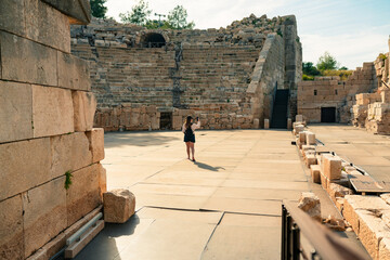 Woman take a photo the ruins of Antique Theater in ancient city Patara, Turkey