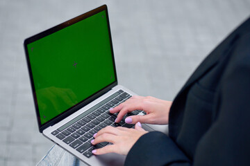 Woman typing message on laptop with green screen