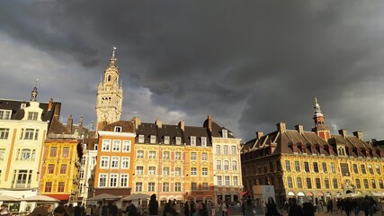 Fototapeta na wymiar Magnifique vue des bâtiments baignés de soleil, Grande-Place de Lille, beffroi en arrière plan, ciel noir