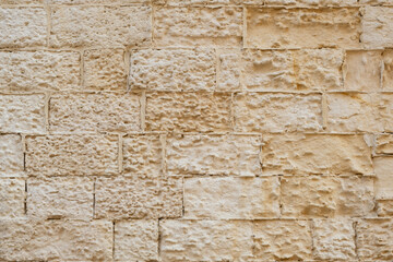 Ancient worn wall made of tuff bricks.