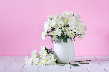 Beautiful bouquet of white chrysanthemums in a vase against a pink background