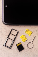 smartphone and open slots for nano SIM cards, two nano SIM cards, micro SD drive and metal key on grey background - 662675599
