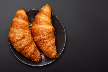 Croissants in a plate on a black background. View from above. French pastries