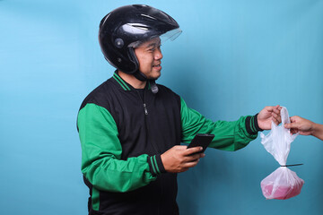 Online taxi driver in uniform jacket and helmet delivering food boxes in plastic bags to a customer at home