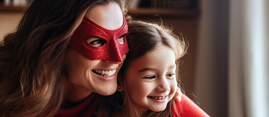 Joyful mother assists daughter in playful superhero activities at home adorned in red cloak and mask during holiday With copyspace for text - Powered by Adobe