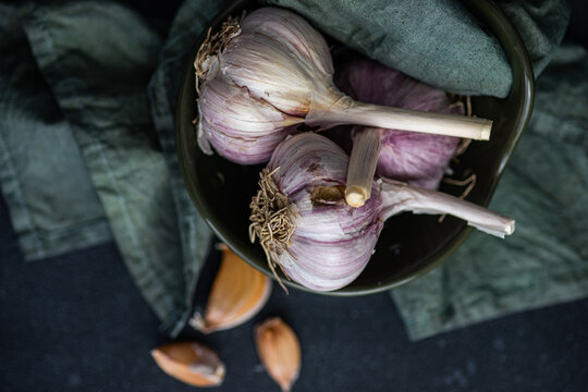 Overhead view of fresh garlic bulbs and cloves in a bowl with a napkin