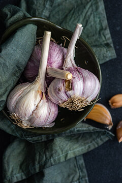 Overhead view of fresh garlic bulbs and cloves  in a bowl with a napkin