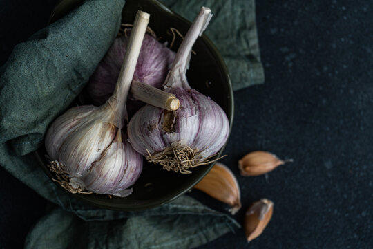 Overhead view of fresh garlic bulbs and cloves in a bowl with a napkin