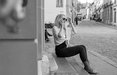 Woman talking to phone in the center of city. Lady sitting on a stairs in Switzerland. Communication concept