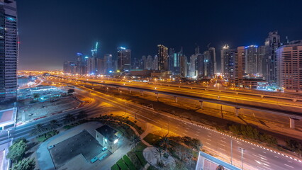 Panorama of Dubai Marina skyscrapers and Sheikh Zayed road with metro railway aerial all night timelapse, United Arab Emirates