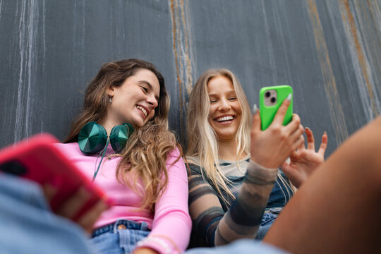 Young stylish generation Z girls spending time outdoors after school. Zoomer students talking and gossiping during lunch break in the school. Importance of education for gen Z.