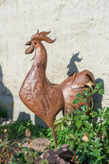 Metal rooster in the garden in the sunlight