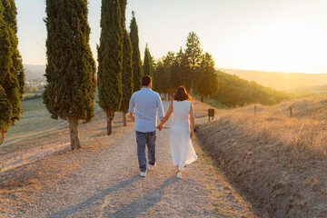 coppia ragazzo e ragazza felici si tengono per la mano su viale al tramonto