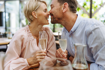 Close up of beautiful couple in restaurant, on romantic date. Wife and husband kissing, having a...