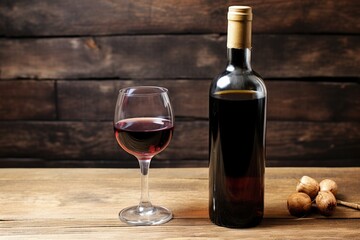 a wine glass next to a bottle on a wooden surface