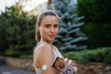 Woman with diabetes connecting her smartphone to continuous glucose monitor sensor before...