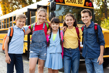 Happy smiling kids waiting next to yellow school bus