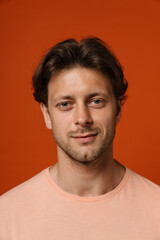 Obraz premium Young man smiling at camera while standing isolated over red background