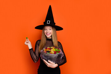 Photo portrait of lovely blonde teen lady hold jelly candy treat trick dressed black halloween garment isolated on orange color background