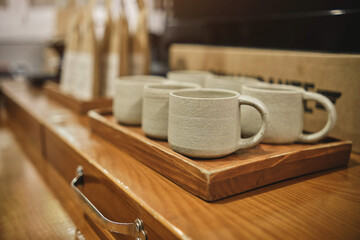 Many coffee cup on table soft focus, glazed ceramic dishes stand on a shelf in the workshop shelving with handmade ceramic and clay mugs.
